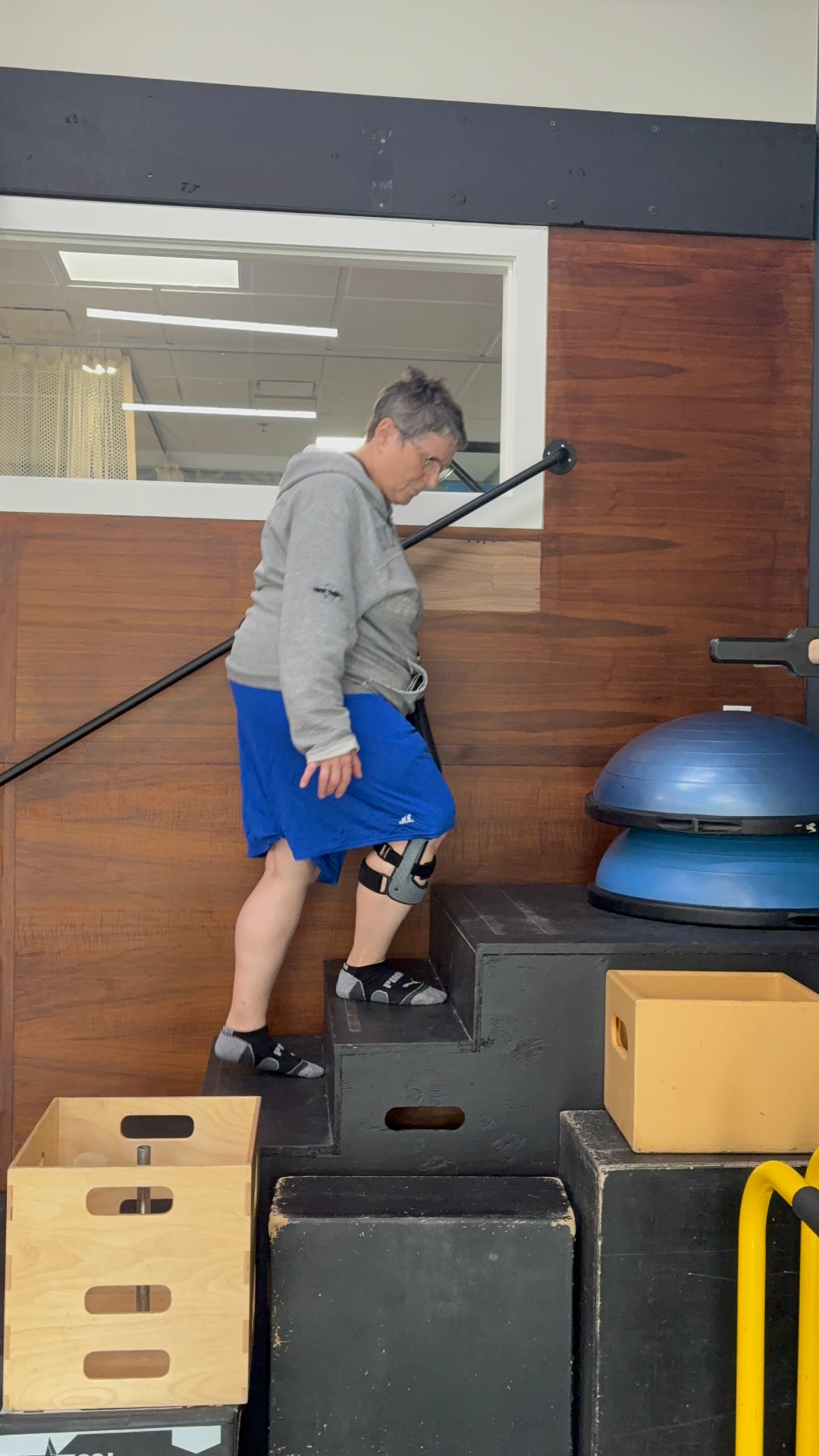 Patient with a knee brace climbing clinic stairs to check gait and fit