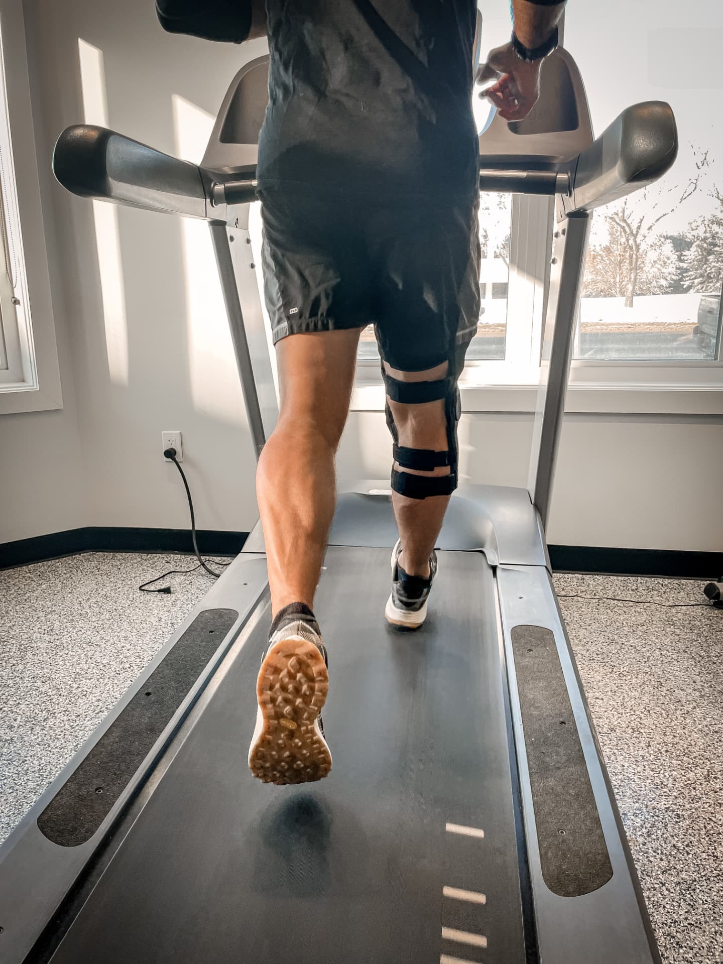 Rear view of a braced knee tracking through a stride on a treadmill